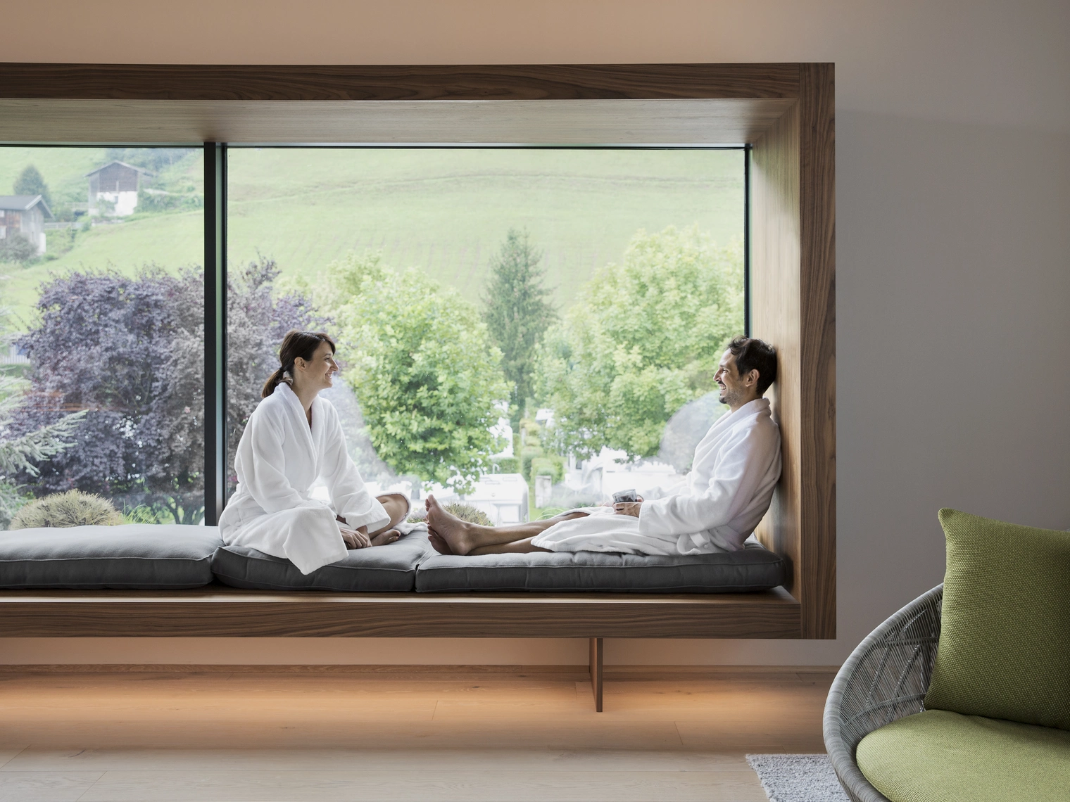 Paar das sich gegenüber auf einer Sitzbank am Fenster sitzen. Natürlich HELL Camping & Aparthotel