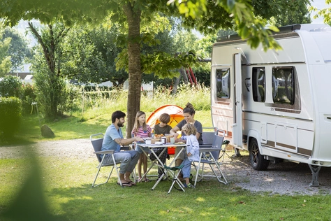 Camper Familie im Sommer beim Essen vor dem Wohnwagen.