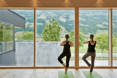 Zwei Personen im Yoga Raum die eine Yoga-Pose ausführen.