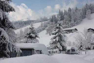 Winterlandschaft in Fügen wo Bäume, Häuser und Wege mit einer Schicht Schnee bedeckt sind.