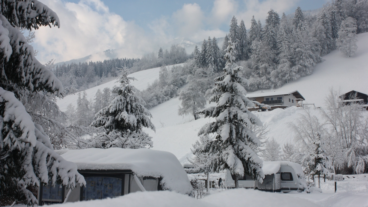 Winterlandschaft ©Natürlich HELL Camping & Aparthotel Winterlandschaft in Fügen wo Bäume, Häuser und Wege mit einer Schicht Schnee bedeckt sind.