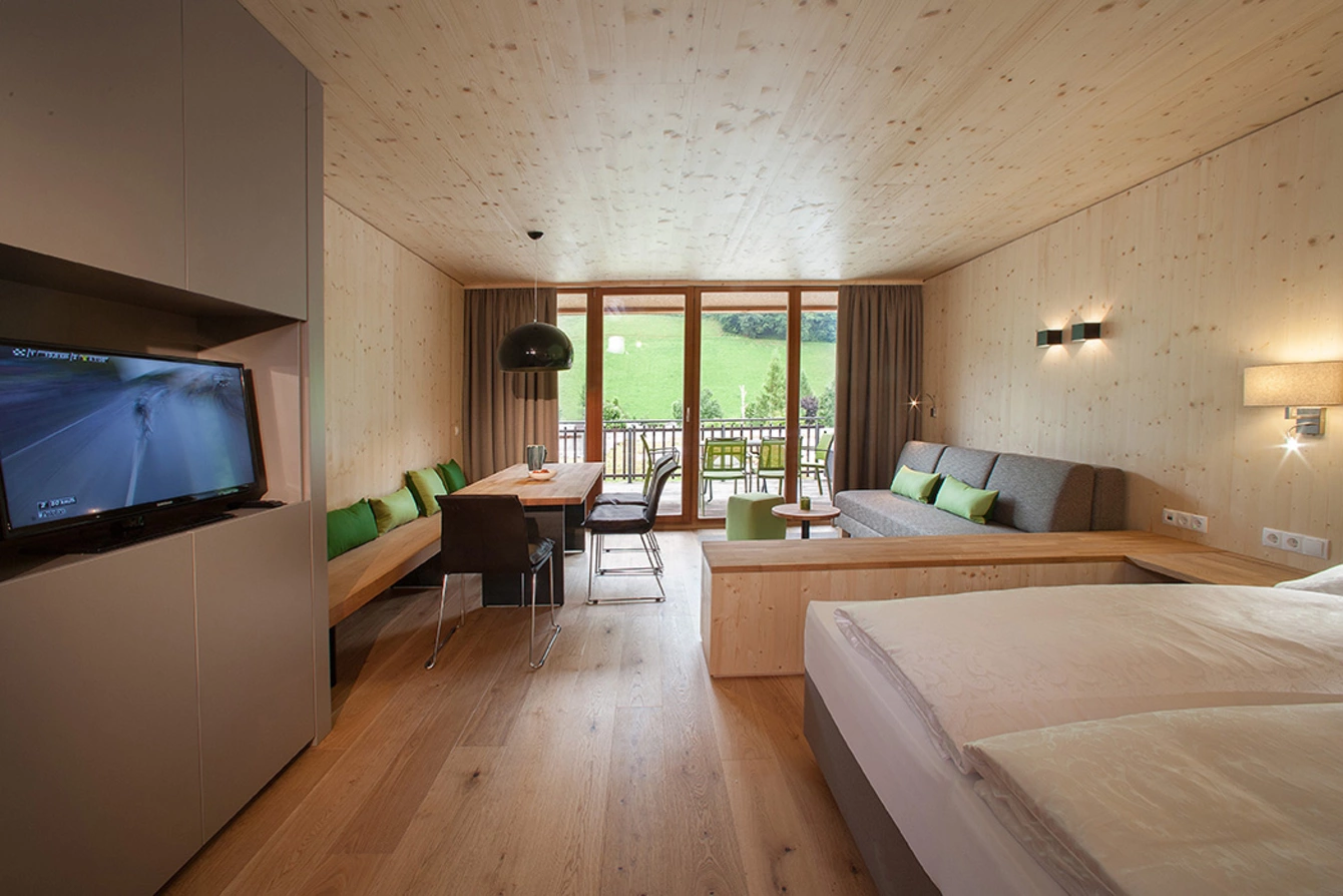 Aberg-maxi ©MG_8692 Gesamtansicht des Aberg-maxi Apartments mit Doppelbett, Wohnbereich, Esstisch und Balkon.