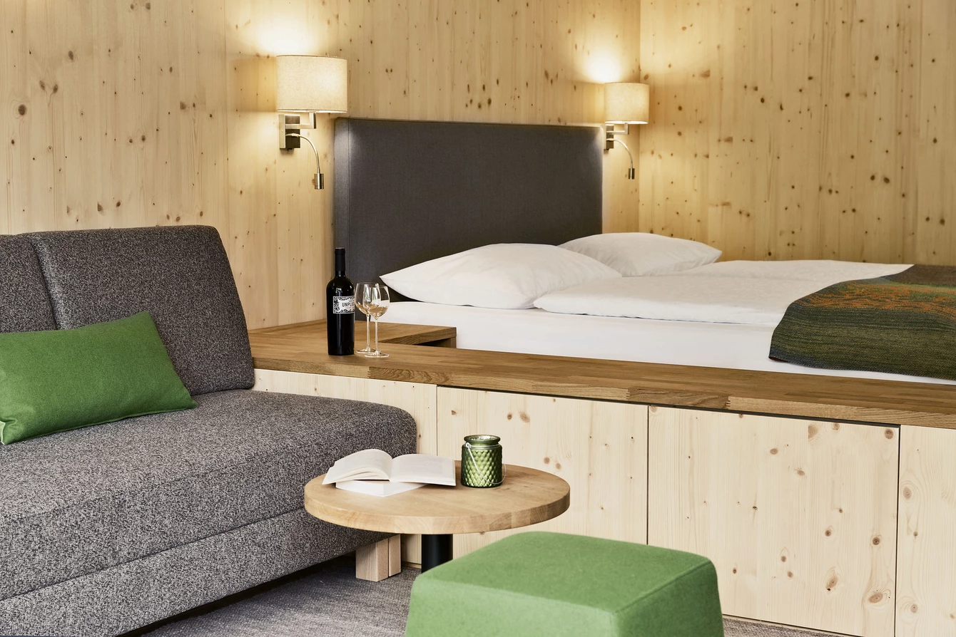 Aberg Maxi Apartment ©Natürlich HELL Camping & Aparthotel Schlafbereich im Aberg-maxi Apartment mit Doppelbett, Sofa, Tisch und warmem Holzambiente.