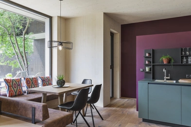 Die helle Küche des Gartenapartments mit einer großen Fensterbank, Esstisch, moderner Küche und dunkler Wand.