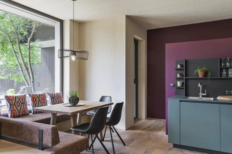 Die helle Küche des Gartenapartments mit einer großen Fensterbank, Esstisch, moderner Küche und dunkler Wand.