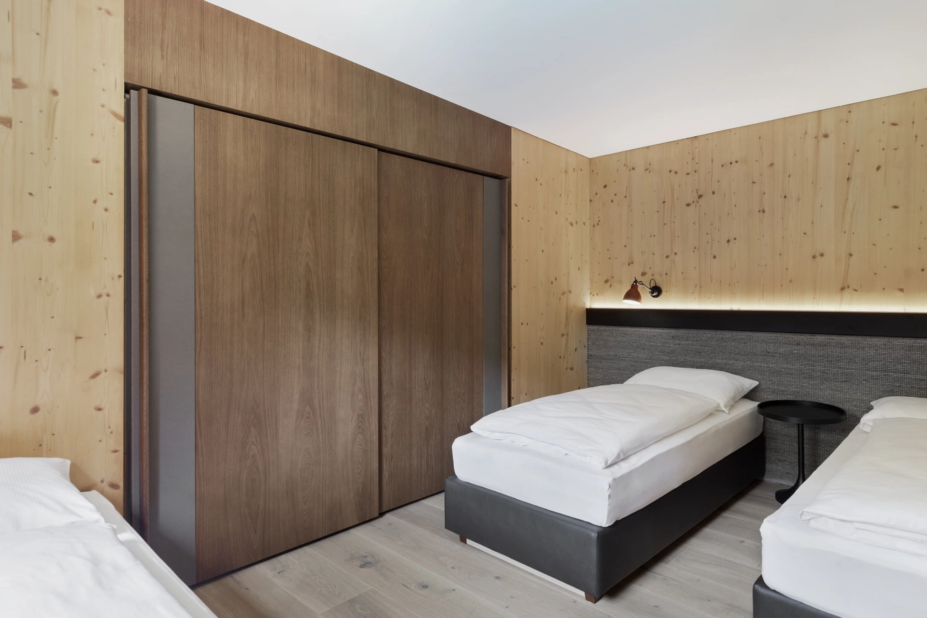 Doppel- & Einzelbetten Garten Lodge ©Natürlich HELL Camping & Aparthotel Doppel- & Einzelbetten im Zimmer der Garten Lodge mit weißer Bettwäsche, Wänden mit Holzoptik und LED-Licht.