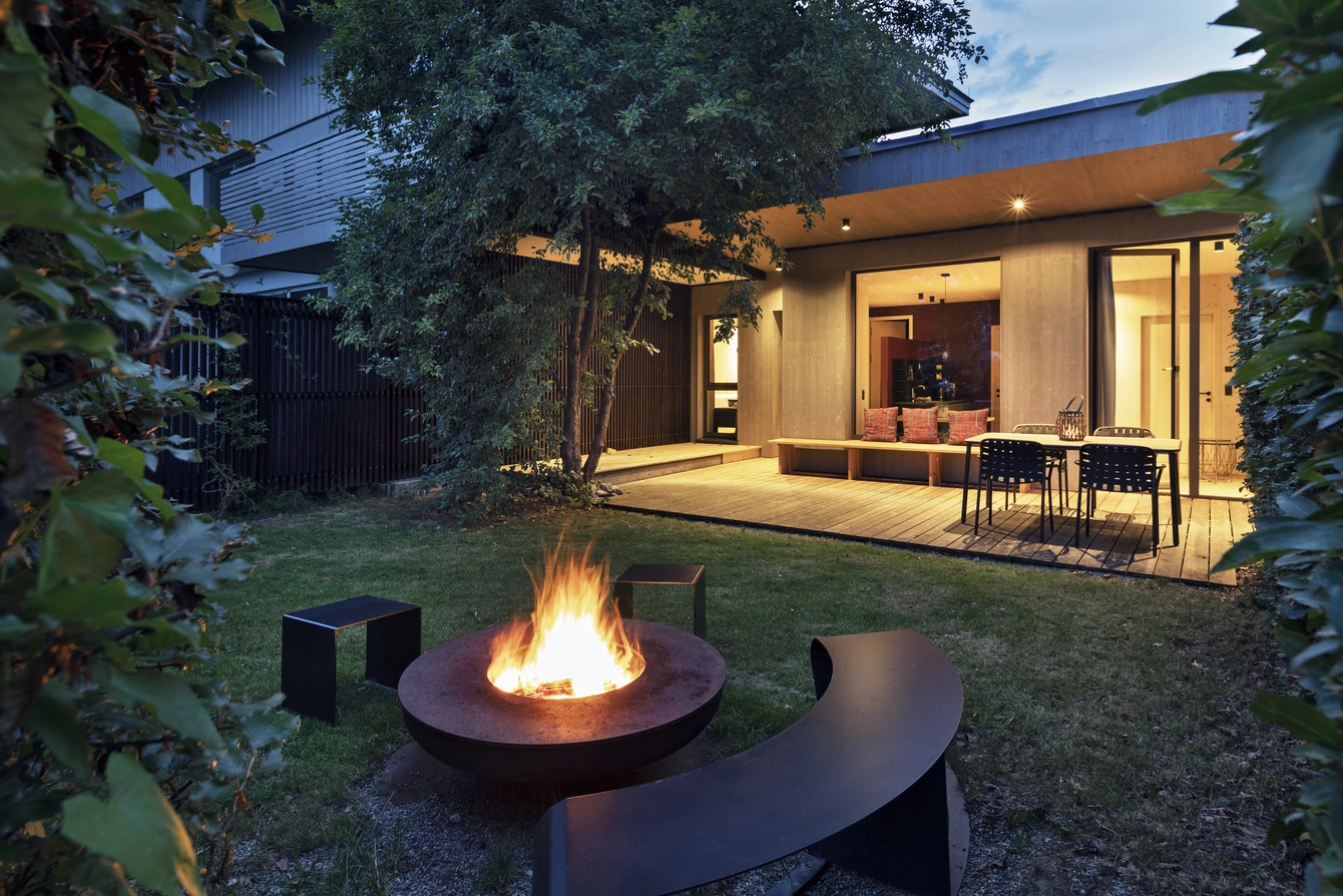 Geräumige Apartments ©Natürlich HELL Camping & Aparthotel Der Garten des Gartenapartments am Abend mit einer Feuerschale und der Terrasse im Hintergrund.