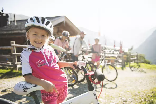 Familienradtour Eine Familie die mit den Fahrrädern vor einer Almhütte Pause macht.