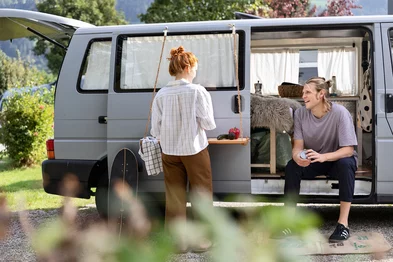 Zwei Personen mit einen VW-Bus beim Campen
