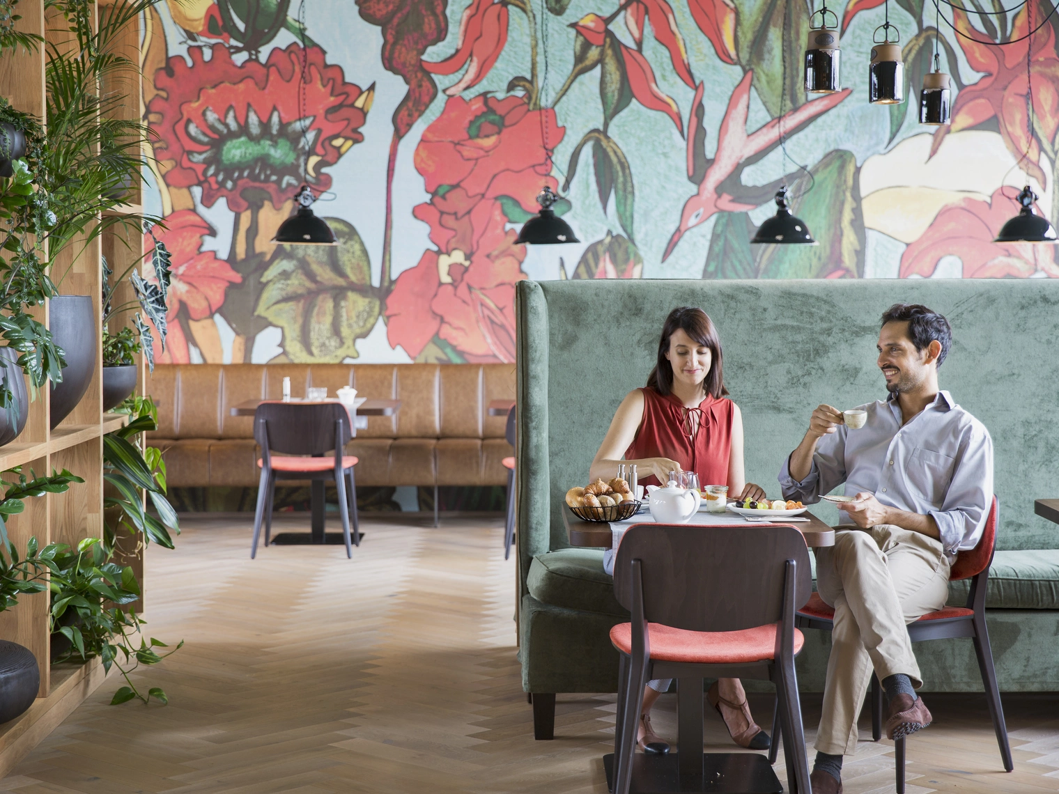 Zwei Personen die im Frühstücksraum des Camping & Aparthotels an einem fein gedeckten Tisch sitzen, und ihr Frühstück, als einzige im Raum, genießen.