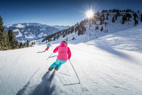 Eine Person die die Piste in Hochzillertal-Kaltenbach hinunterfährt.